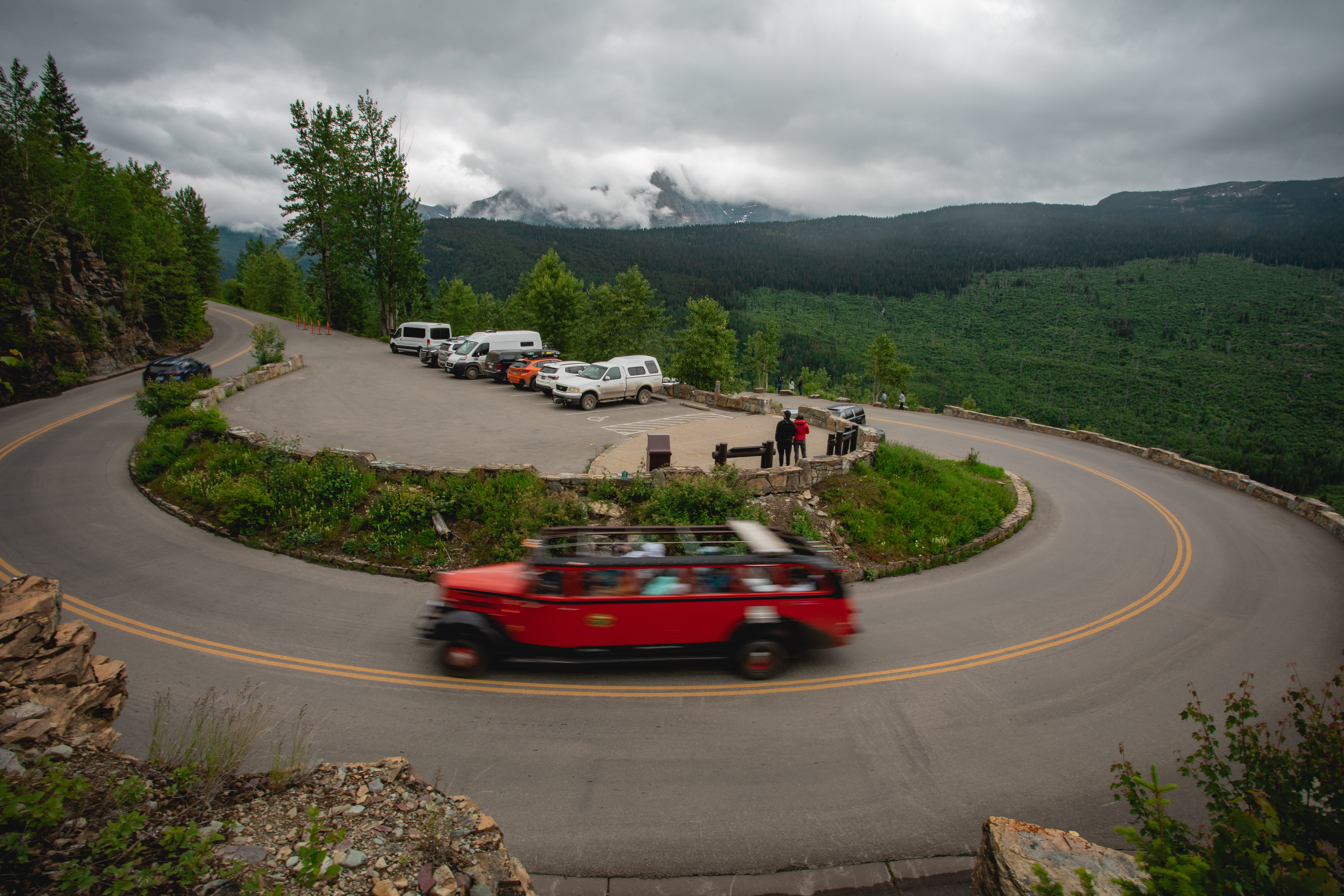 A red car driving along a road with a large turn.