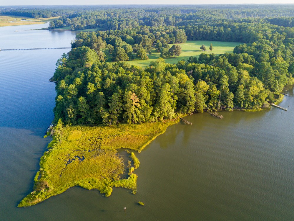 Arial view  of a green peninsula jutting out into bay area