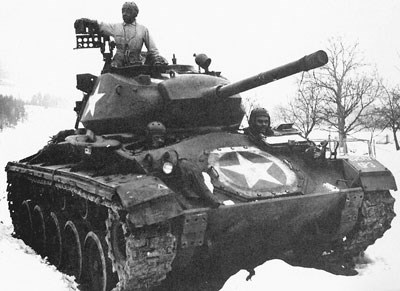 A large tank with several tankers sitting in and atop the tank while parked in the snow
