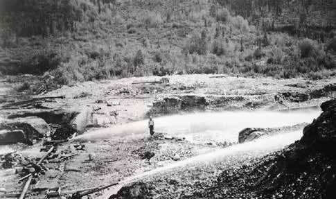 man standing in a valley near a hose spurting water