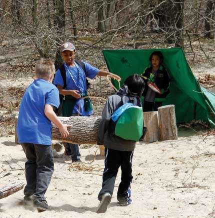 Children create a shelter using tarps and logs at the Nature Play Zone
