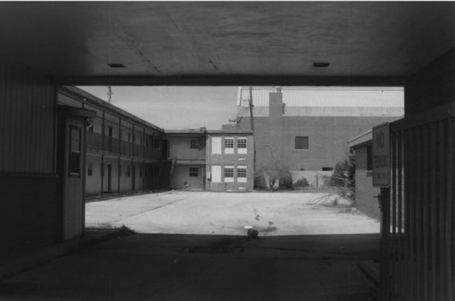 open courtyard of a tow story hotel building with a car port open to access the parking spaces by the rooms within the courtyard.
