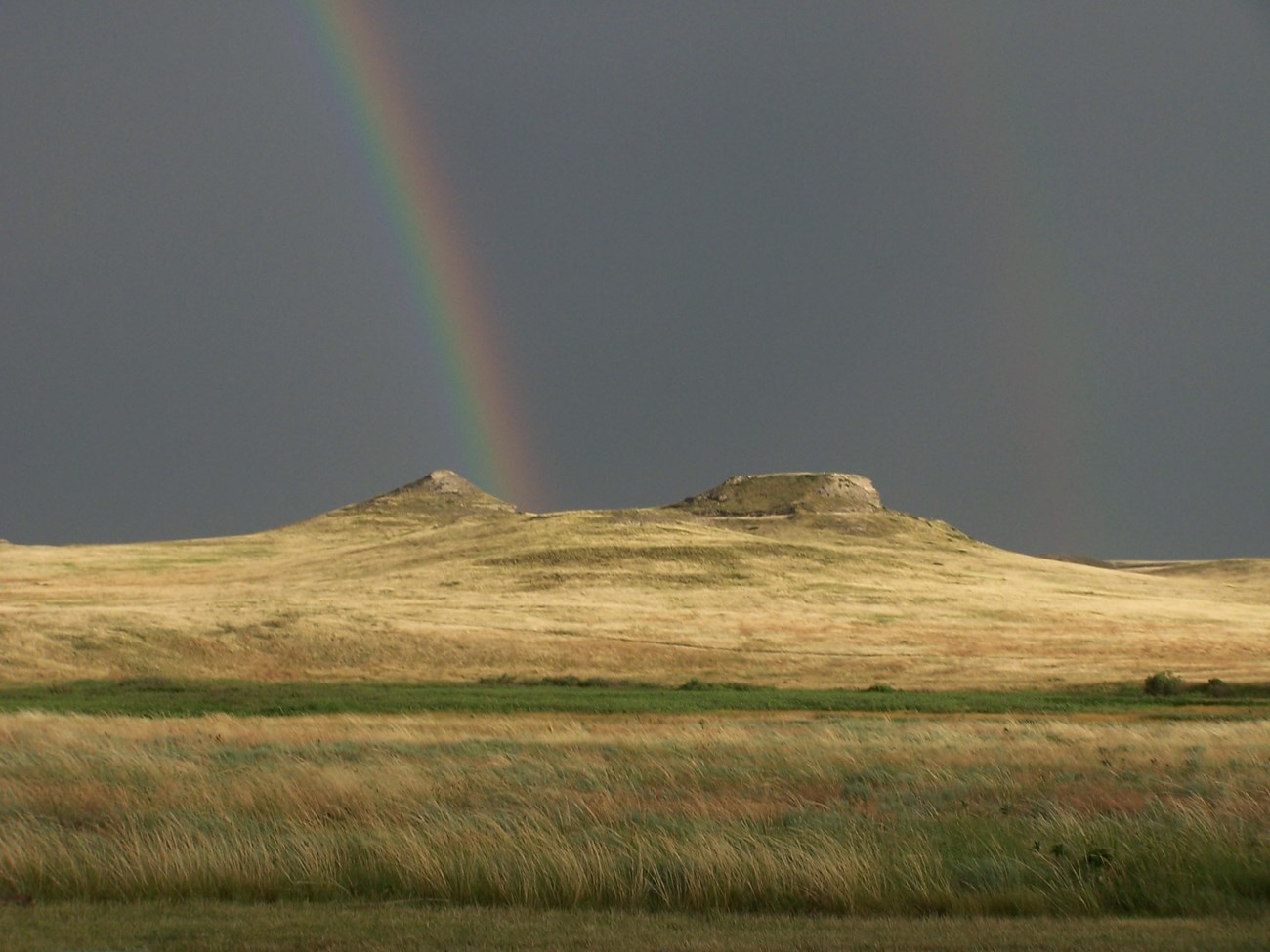 Double rainbow over a hill in a prairie