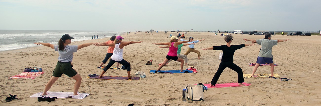Group doing yoga on the beach with a ranger