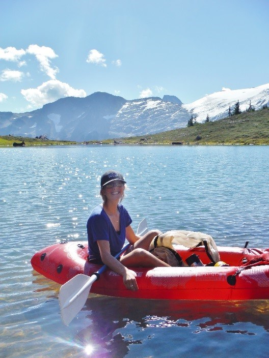 Researcher in a bright red inflatable boat on a sparkling mountain lake