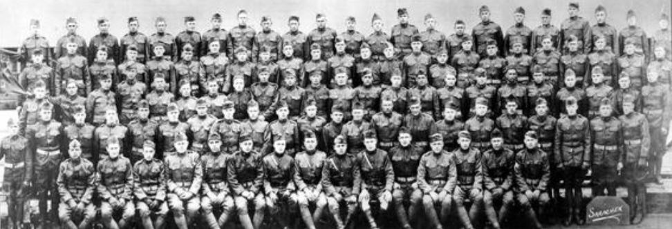 A large group of men in army uniform pose for a photo