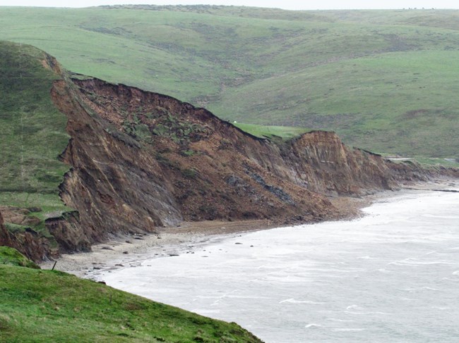 Collapsed section of a coastal cliff, consuming a large section of the beach below