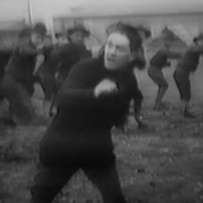 A man standing in a boxing position with many other men behind him