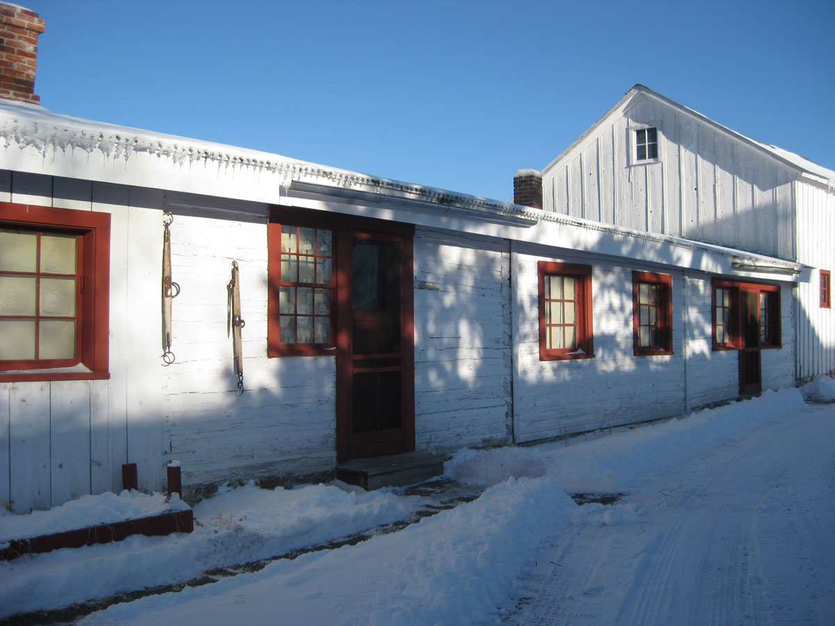 Bunkhouse with afternoon shadows on clear, snow covered winter day.