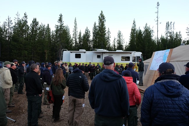 A group gathered around a person near a map.
