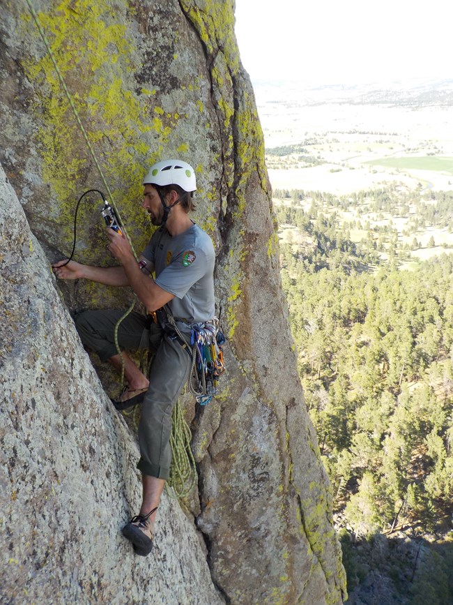 A properly equipped climber using a device to look into a crack on Devils Tower