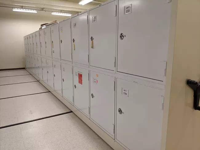 Collection storage lockers along a white floor and bright lights.