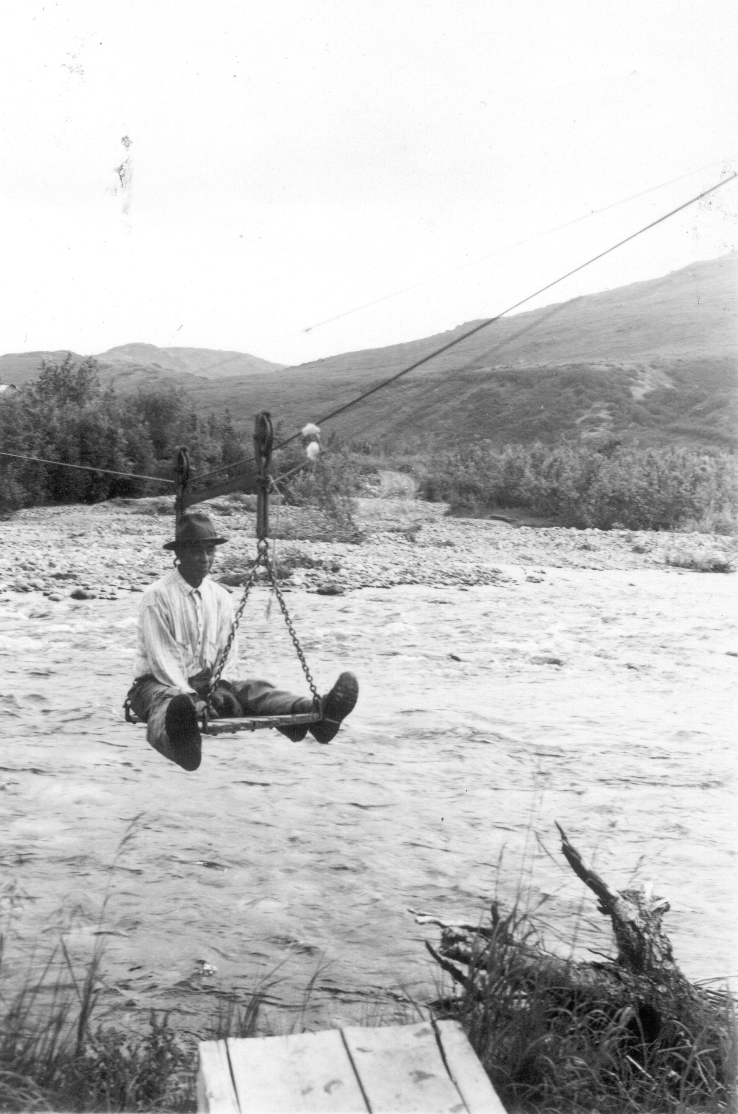 man riding on a tramway over a creek