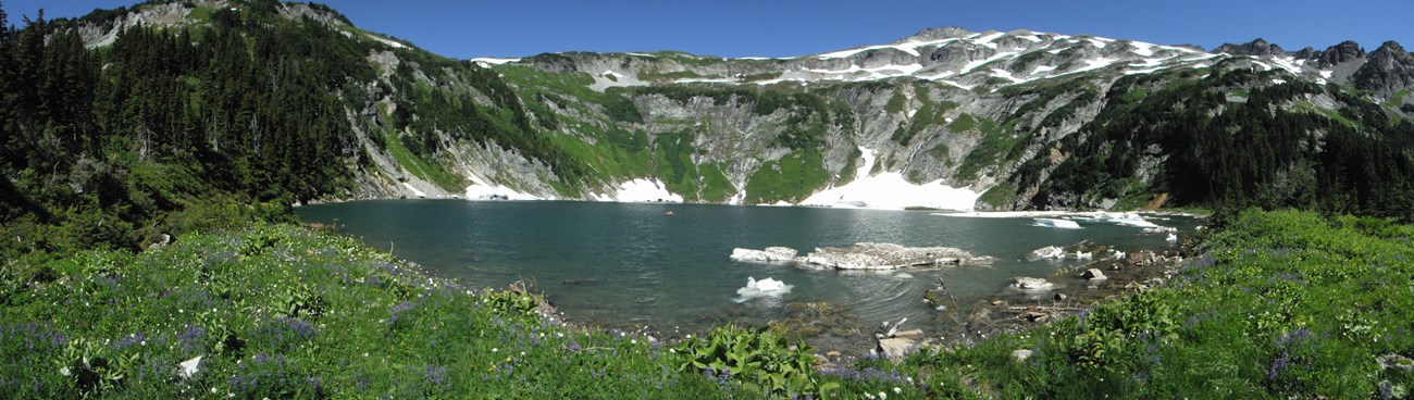 Panorama of a turquoise lake nestled among mountain peaks