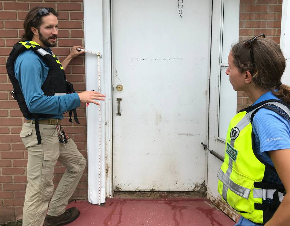 Man and woman talk outside a front door with flood damage