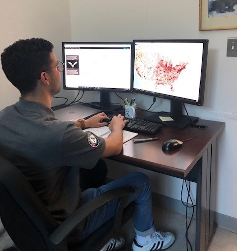 Eddie sits a desk in front of two monitors while he creates a story map
