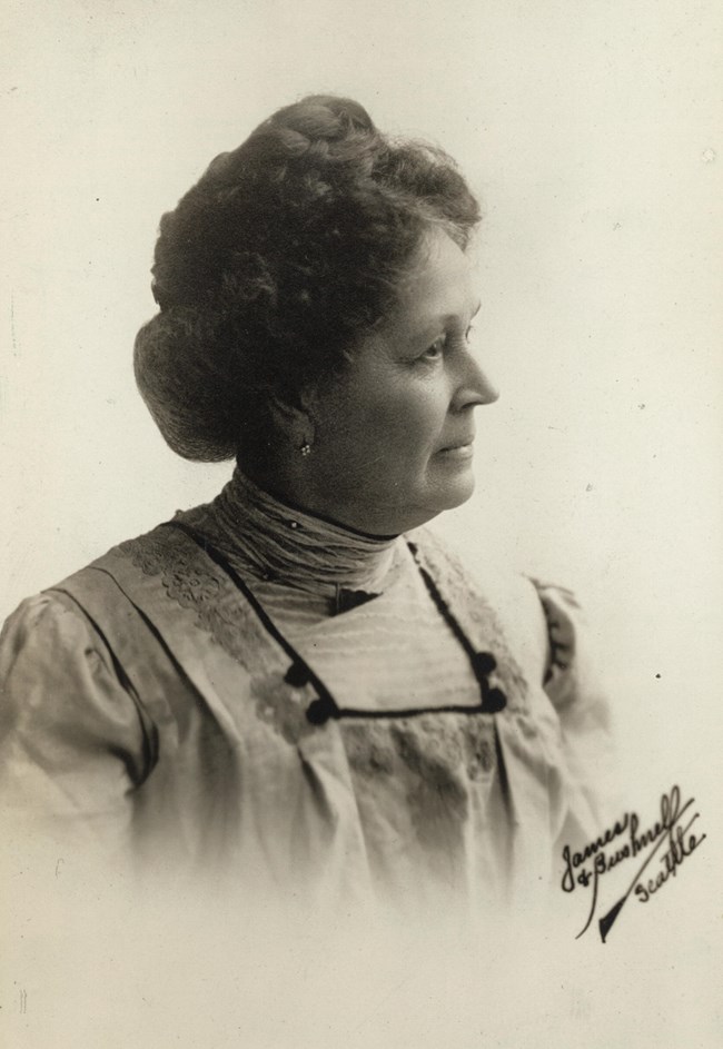 Formal portrait, head and shoulders, Emma Smith Devoe of Seattle, Washington, facing front with head turned in profile to right, wearing high-neck collar.