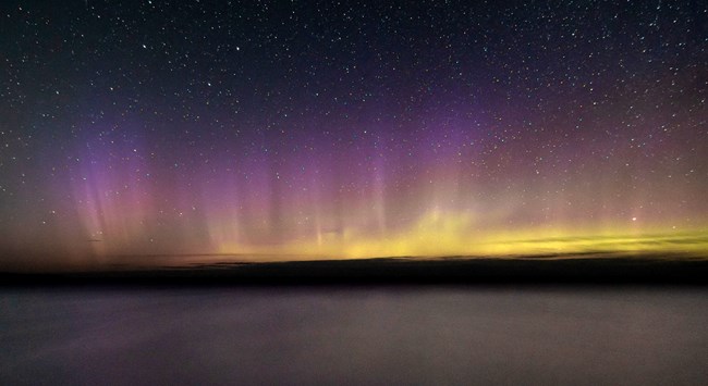 Northern Lights shinning across the lakes in shades of yellow and purple