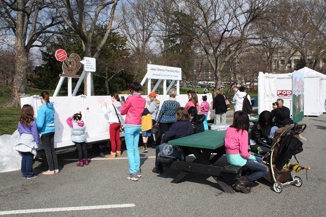 Children draw on the Friendship Mural at the welcome area