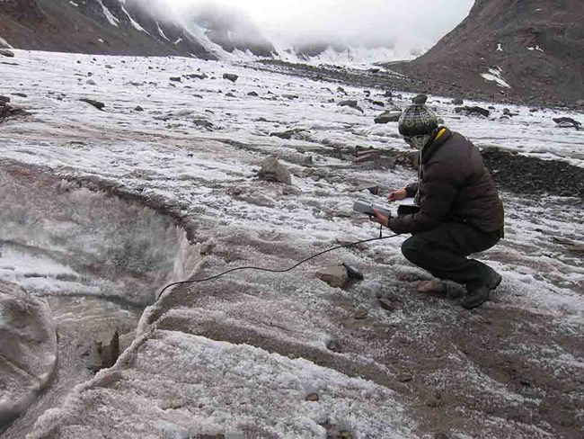 A researcher takes measurements at a snowfield high in the Brooks Range.