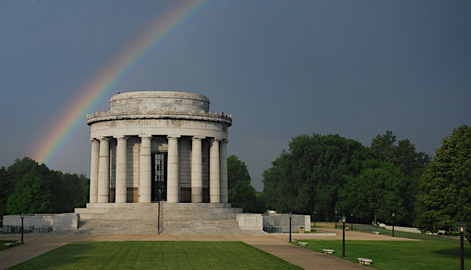 Memorial building in park setting with rainbow overhead
