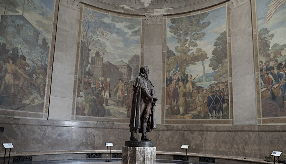 Statue of 18th century man in round memorial room surrounded by murals