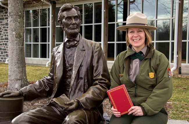 Barbara Sanders sitting next to a statue of Abraham Lincoln