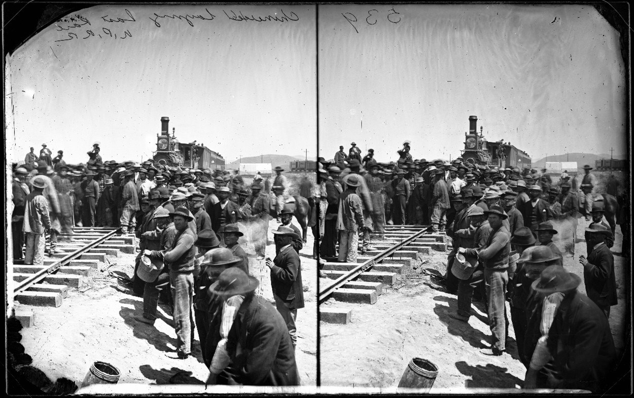 A crowd of Chinese workers along a railway with a train in the background