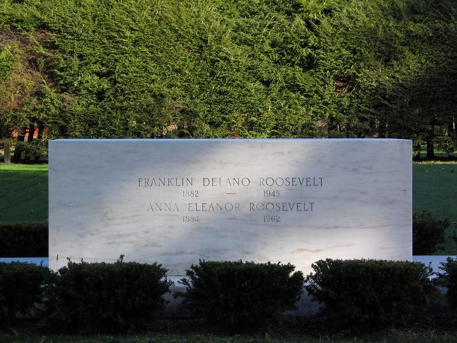 A marble block on a lawn engraved with Franklin and Eleanor Roosevelts' names.