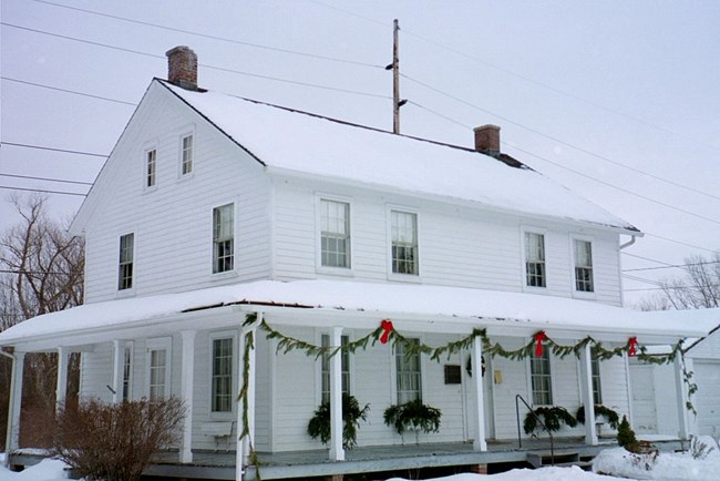 Exterior of a white, wooden house in winter