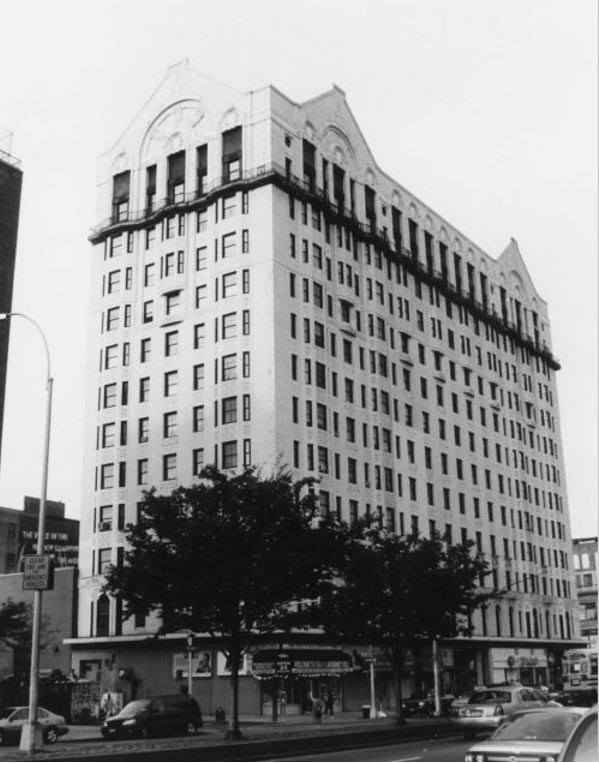 13 story hotel building with two trees in front of the entrance and cars on the city block