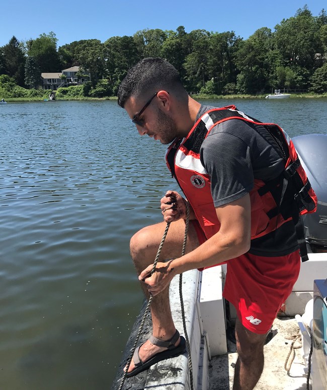 Eddie pulls up a rope containing a sediment sample from the ocean bottom onto a boat he is standing in