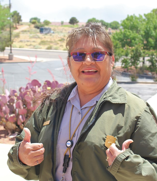 Person posing with thumbs up outside.