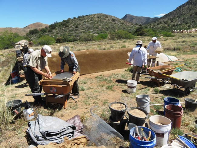 A NPS maintenance staff member, a NPS volunteer, and 3 Cornerstones staff members complete a preservation effort on a corral wall.