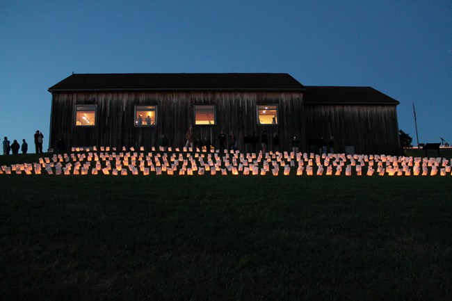 Luminaries cast a solemn glow in the twilight at Johnstown Flood National Memorial.