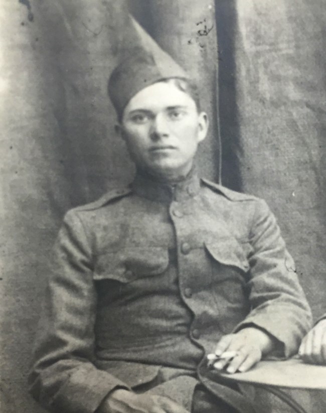 Photo of man in private's uniform sitting at a table