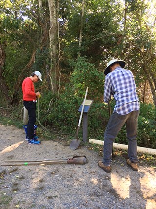Two people work on a hard-packed dirt trail.
