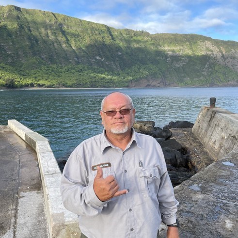 Man in front of a green mountain and water