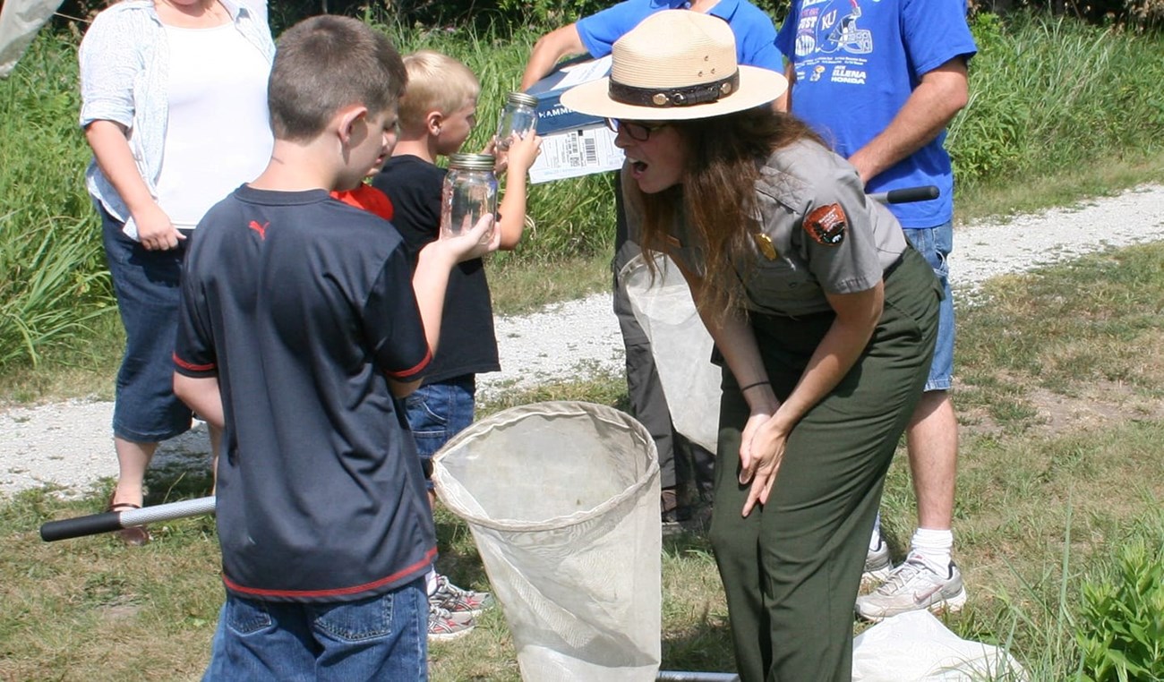 Park Ranger and child look at insect in jar