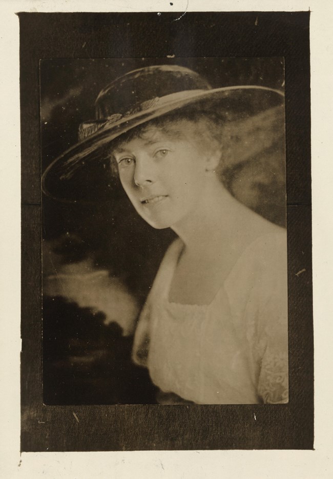 Formal portrait, head and chest, Katherine Morey, facing left with head turned toward camera, wearing wide-brimmed hat.