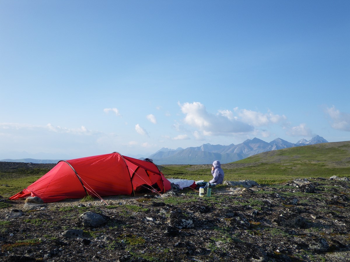 Image of tent and camper on mountainside.
