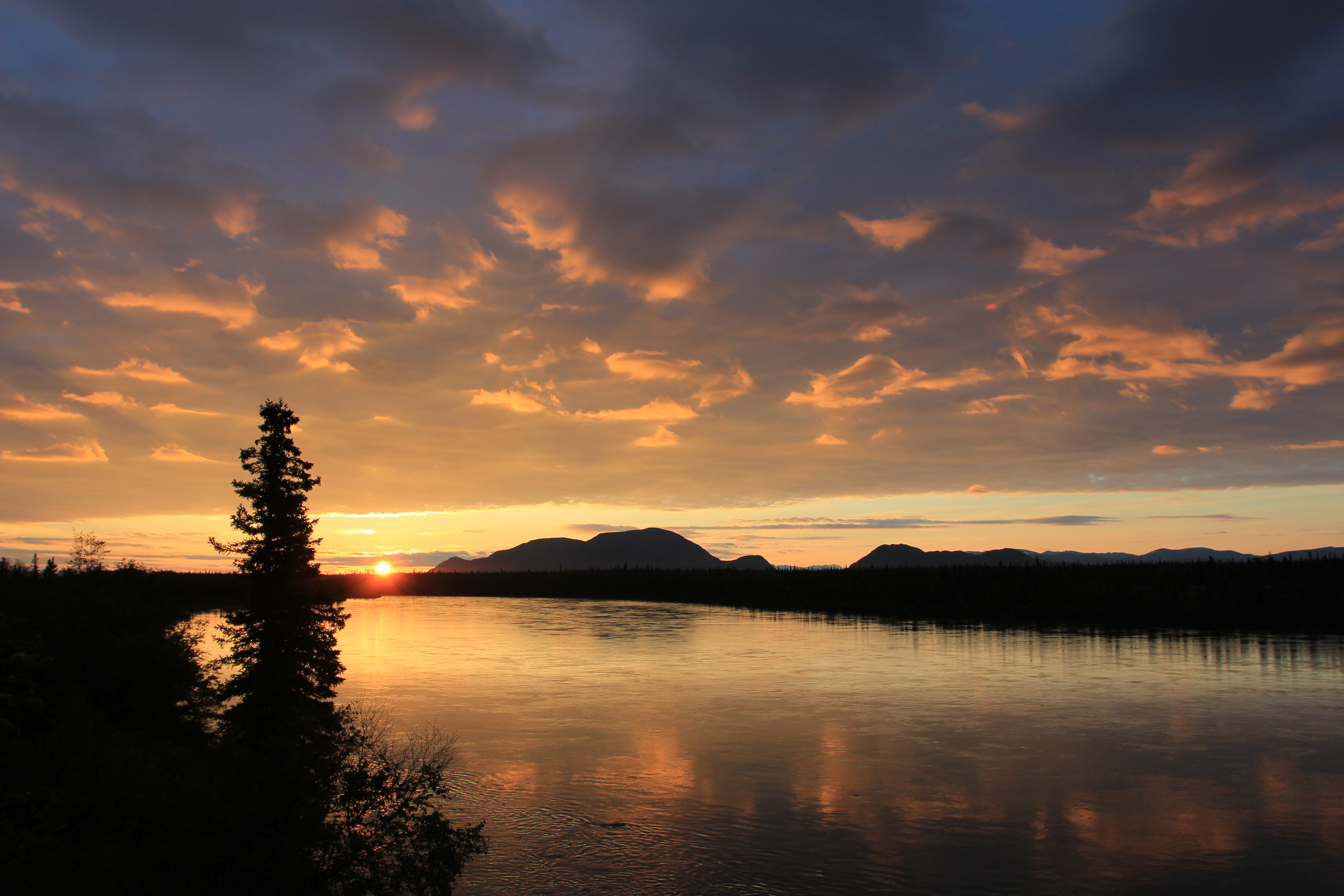 Orange and gray clouds over a river at sunset