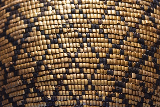 Close up of a woven basket with an intricate diamond pattern in brown and dark brown.