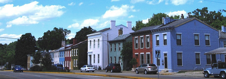 Colorful town house fronts with a street in front.