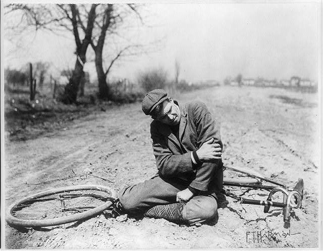 A man on the ground after falling off of his bike.