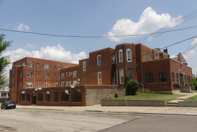 large geometrically shaped brick building with satellite dishes attached to the street level entrance.