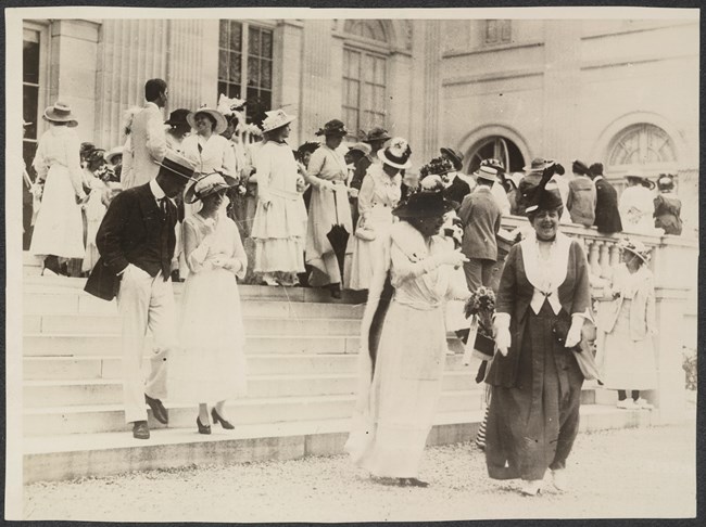 Photograph of women and men on steps leading up to Marble House, Alva Belmont's estate in Newport, RI.