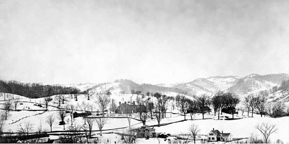 Black and white photo of a small town with a mountain in the distance.