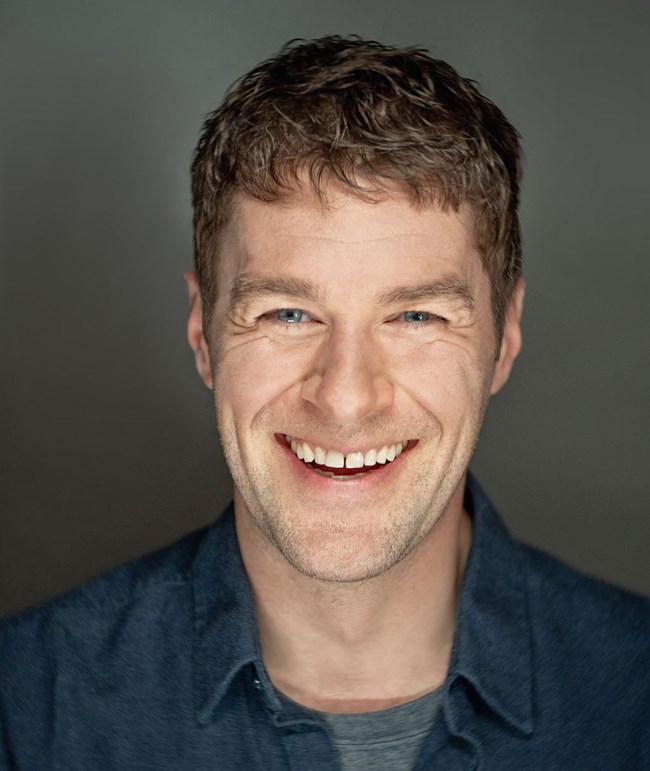 A man in a blue shirt smiling.