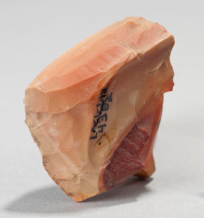 Image of an archeological artifact, a peach colored stone with lines, arrow points.